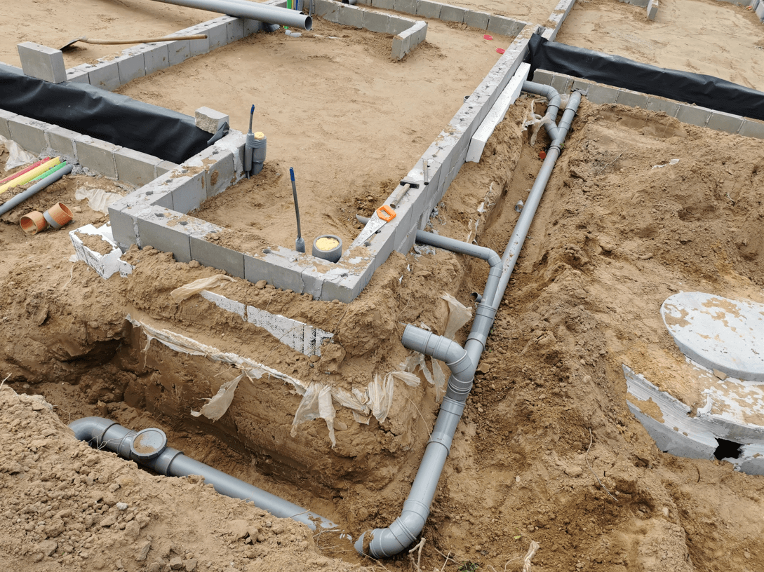 Aangelegde riolering met pvc-buizen in de grond rond een woning