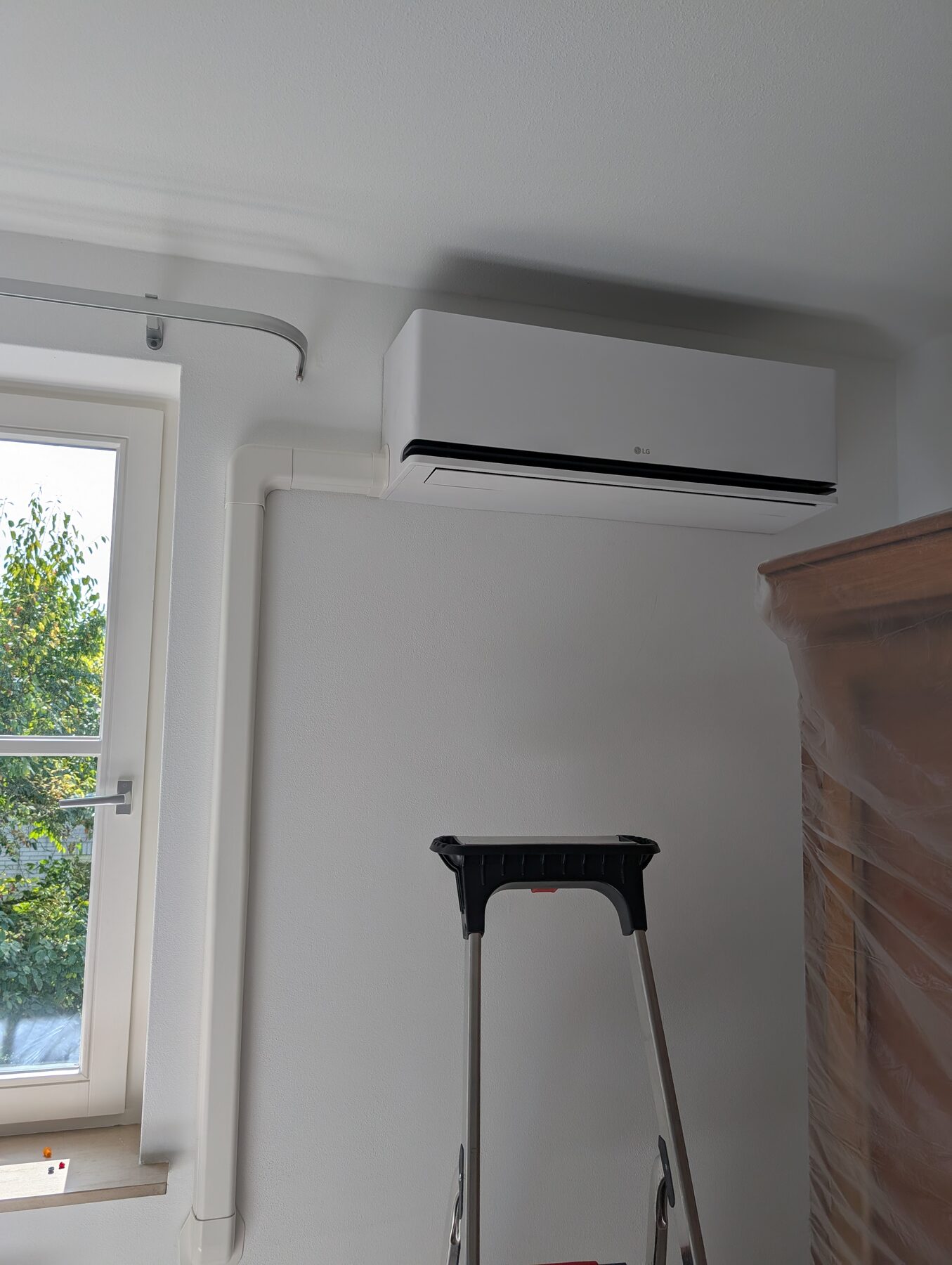 Airco-binnenunit geplaatst boven het raam in een woonkamer