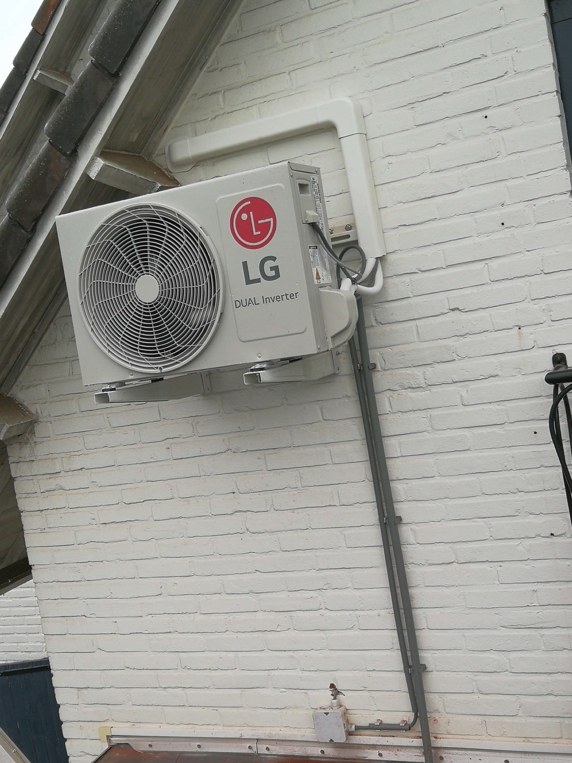LG DUAL Inverter airco-buitenunit geplaatst tegen een wit geschilderde gevel