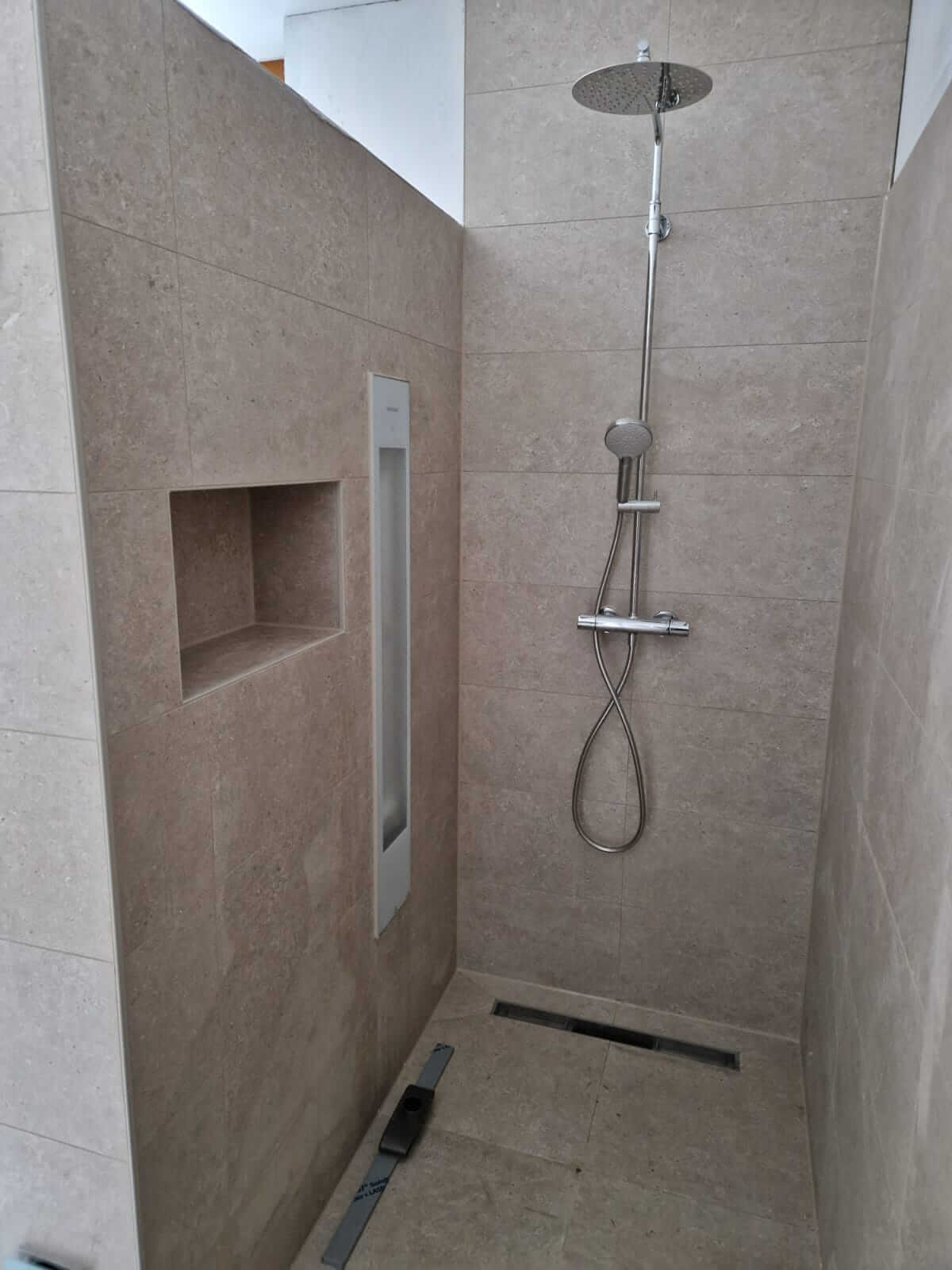 Betegelde inloopdouche met regendouche, nis en douchegoot, aangelegd in een badkamer